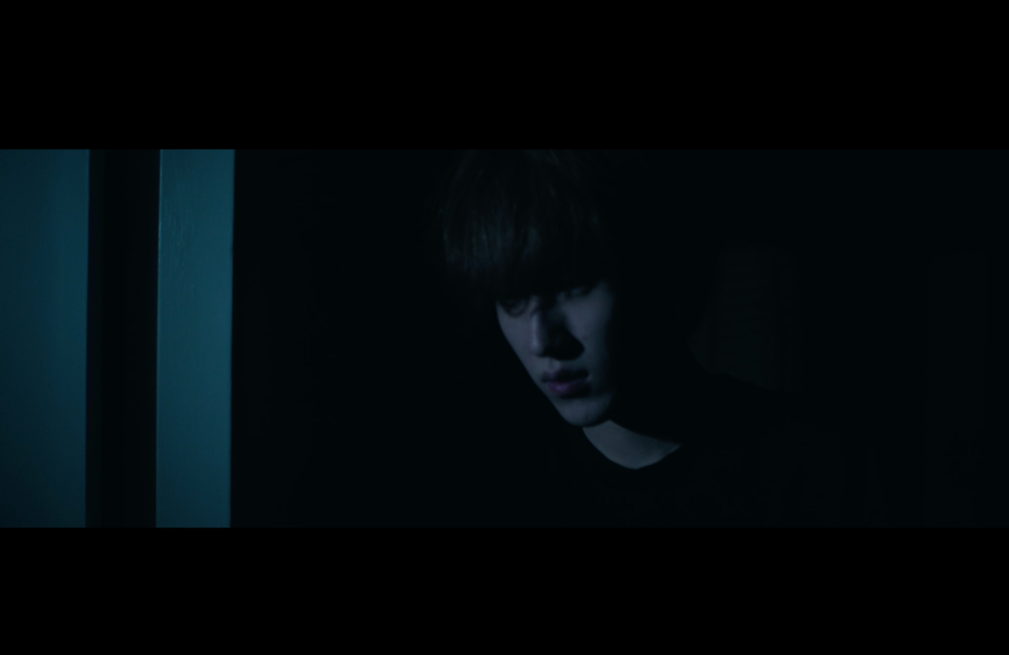 A man emerges from shadow beside a doorway